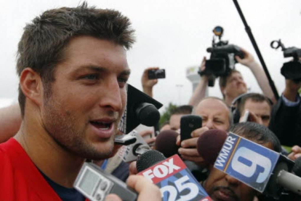 Tim Tebow has a very brief encounter with reporters. Photos: Reuters