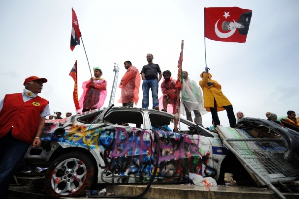 Anti-government protesters holding Turkish flags stand at the entrance of Gezi park on the landmark Taksim square in central Istanbul. Photo: AFP