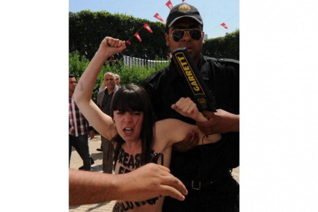 A Tunisian security guard arrests one of three Femen activists protesting in front of the Ministry of Justice in Tunis. Photo: EPA
