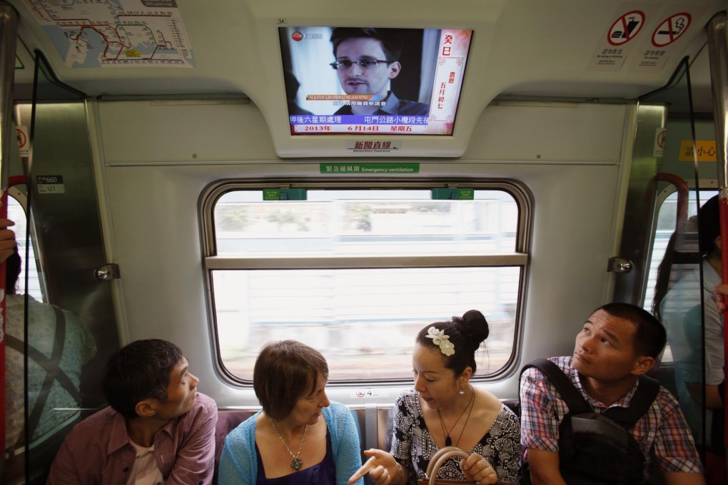 Train passengers watch news of Edward Snowden, the US whistle-blower who is hiding in Hong Kong. Photo: Reuters