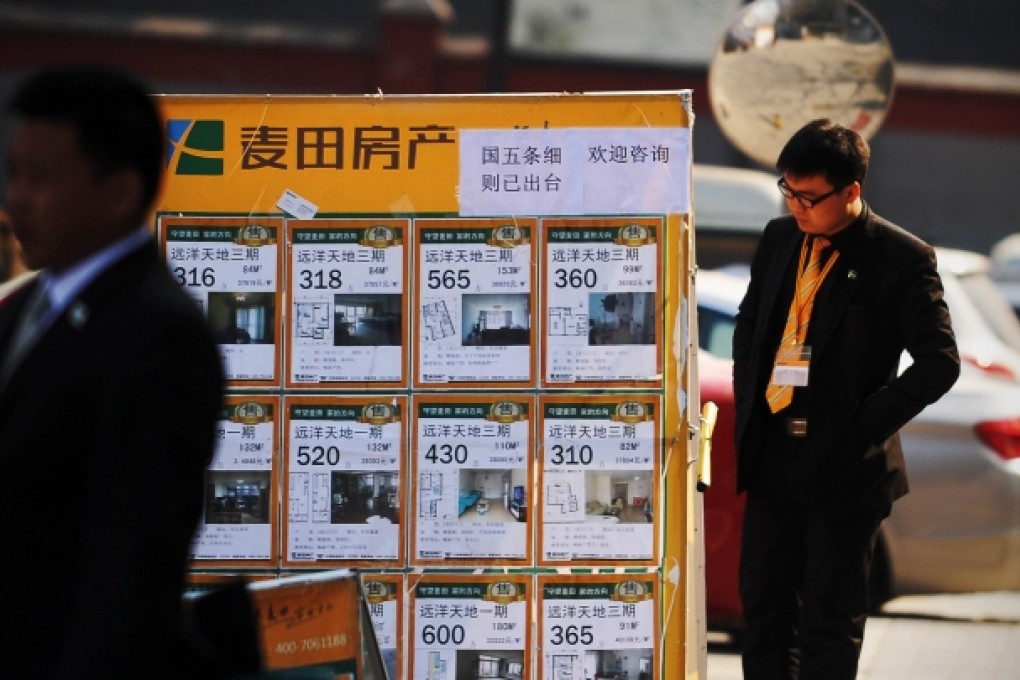 A real estate agent checks a property advertising board in Beijing. Photo: AFP