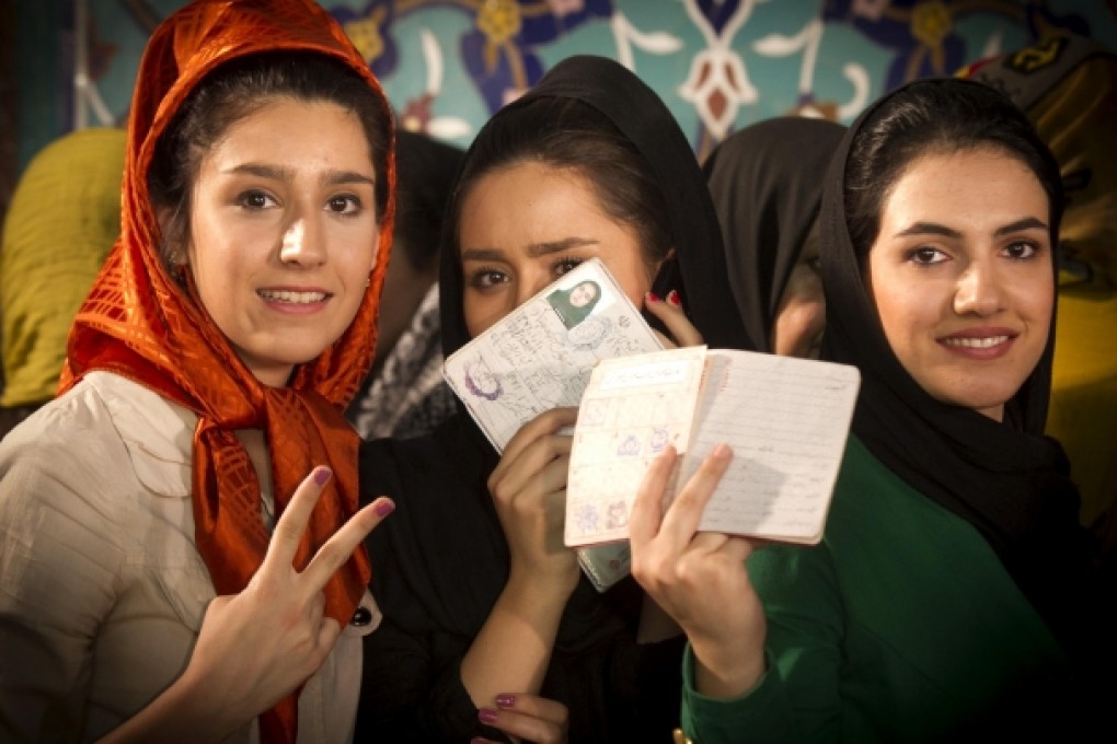 Iranian women display their identity cards before casting their ballots in the presidential election at a polling station in northern Tehran. Photo: Xinhua