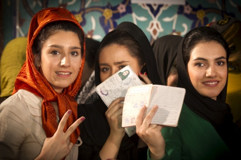 Iranian voters display their identity cards before casting their ballots at a polling station in northern Tehran. Photo: Xinhua