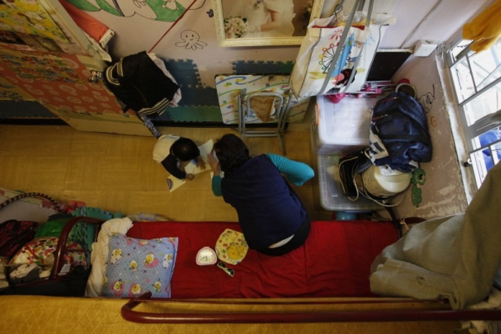 A single mother plays with her daughter in the bedroom of an 80 square-foot sub-divided flat. Photo: Reuters
