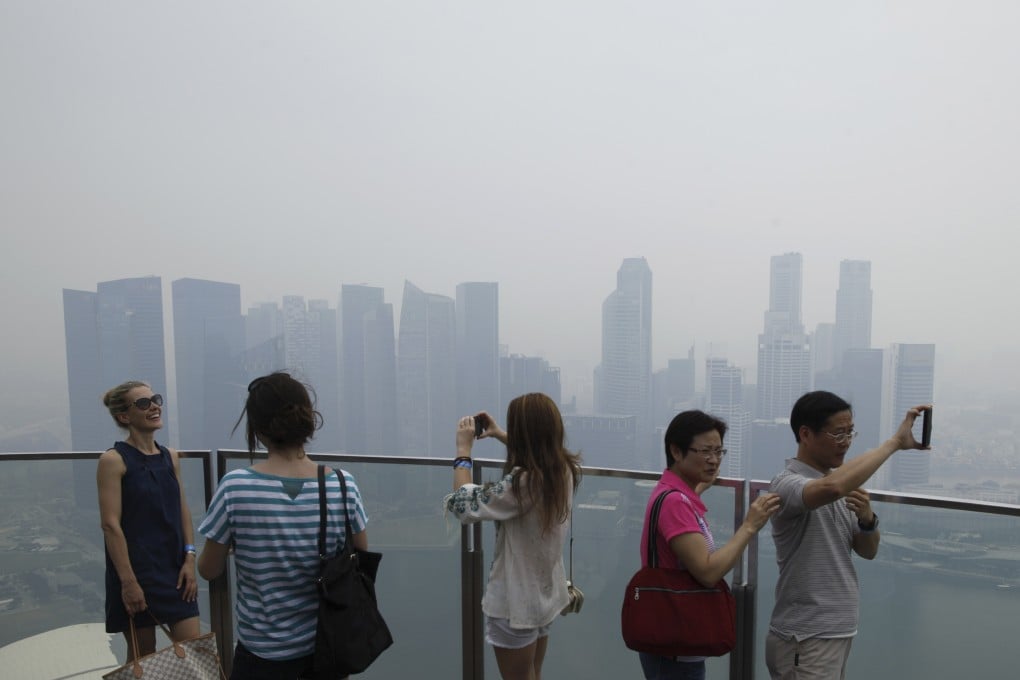Visitors take photos on an observation deck at the Marina Bay Sands Skypark overlooking the haze covered skyline of Singapore. Photo: Reuters