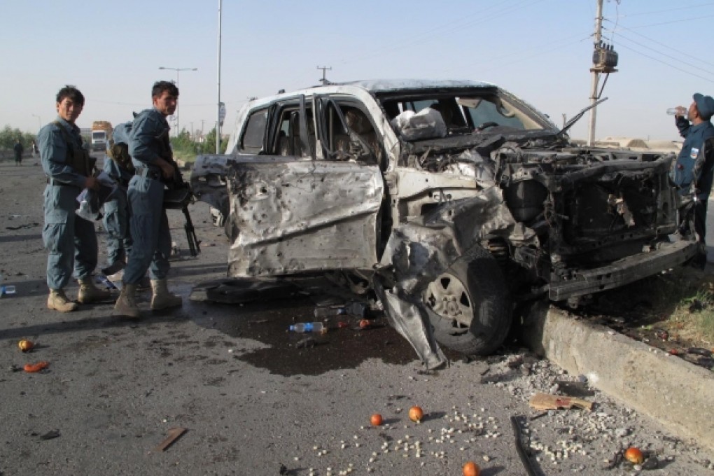 Afghan policemen gather around a damaged armed vehicle at the site of the suicide car bombing in Helmand province, Afghanistan. Photo: Xinhua