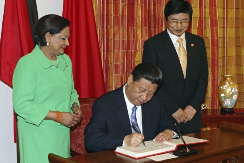 Chinese President Xi Jinping, center, signs the guest book watched by Trinidad and Tobago's Prime Minister Kamla Persad-Bissessar, left, at the Diplomatic Center in St. Ann's, Trinidad. Photo: AP