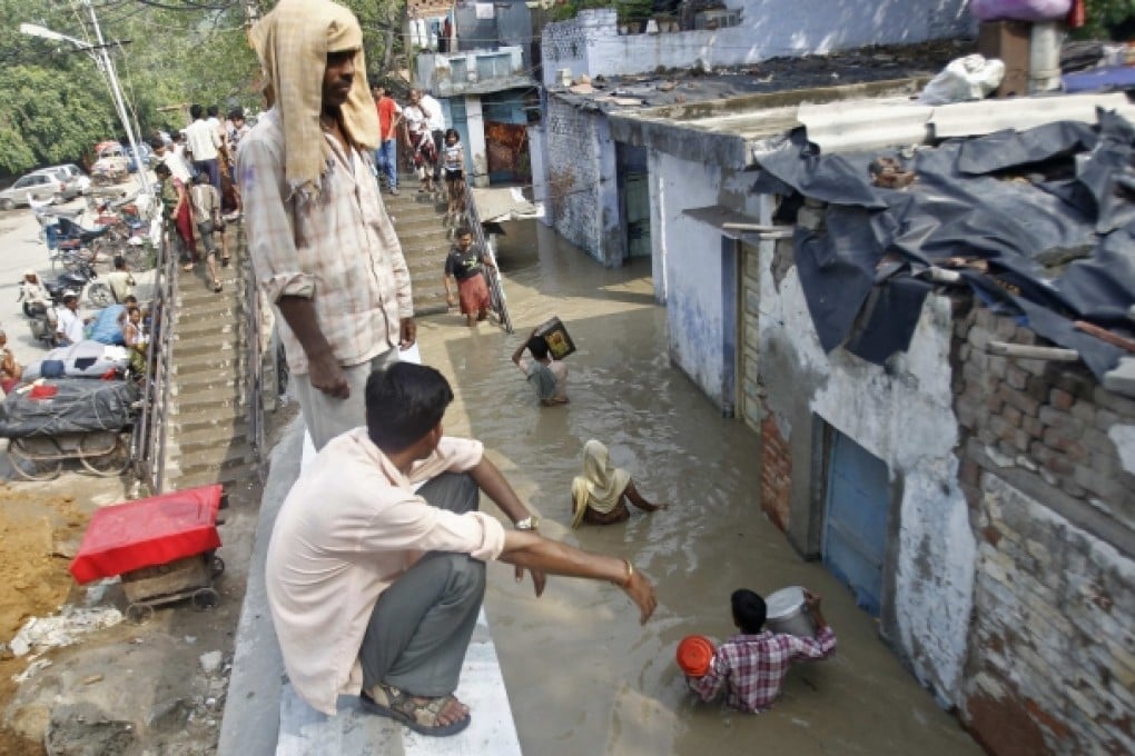 Residents carry their belongings through an alley flooded with the rising water level of river Yamuna after heavy monsoon rains in New Delhi. Photo: Reuters