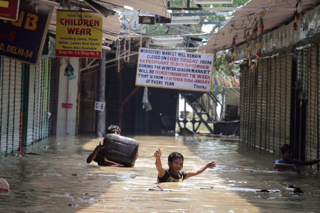Locals wade through floodwaters close to the Yamuna River in New Delhi. Flooding has hit many areas in India this week. Photo: EPA