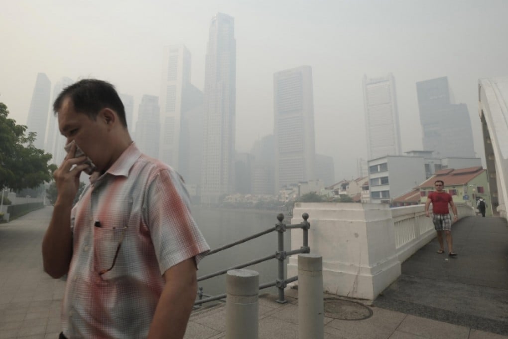 A man covers his nose and people are being urged to stay indoors as an acrid-smelling haze blankets Singapore. Photo: AP