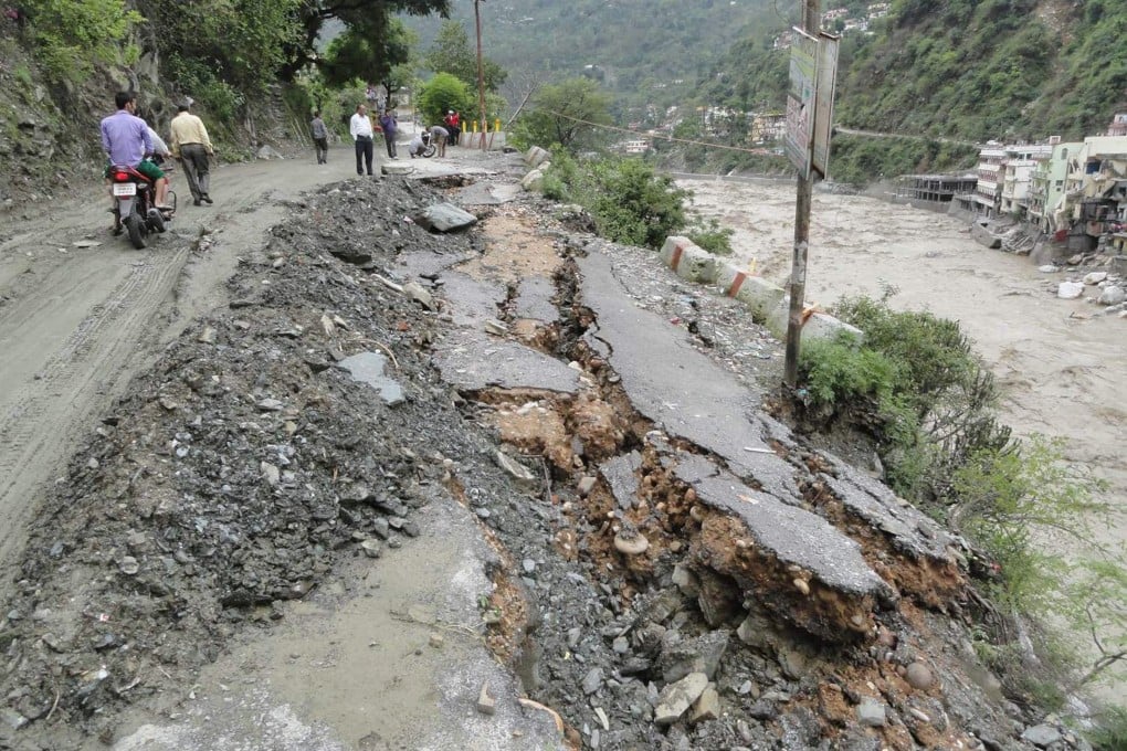 People walk along a damaged road after heavy rains in the Himalayan state of Uttarakhand. Thousands stranded in parts of northern India awaited rescuers. Photo: AFP