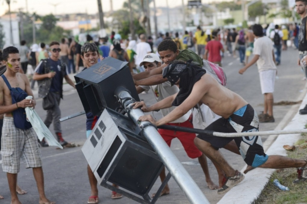 Demonstrators tear down a traffic light during clashes with riot police near the Estadio Castelao in Fortaleza. Photo: Reuters