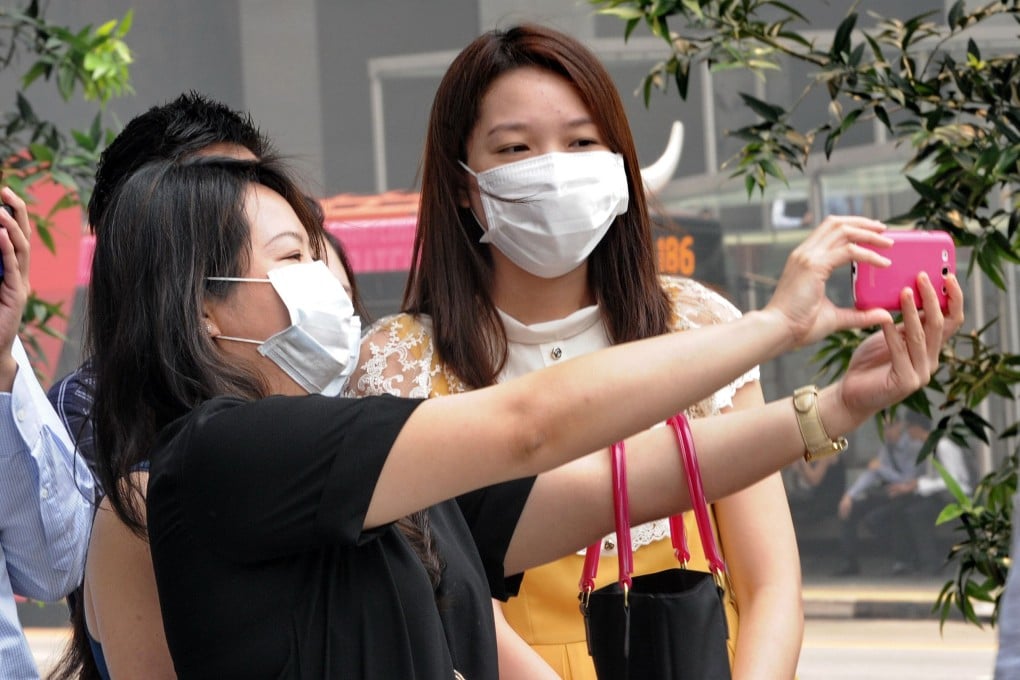 A group of office workers wearing face masks take a picture in Singapore on Thursday. Singapore has demanded action by Indonesia on fires raging in Sumatra. Photo: AFP