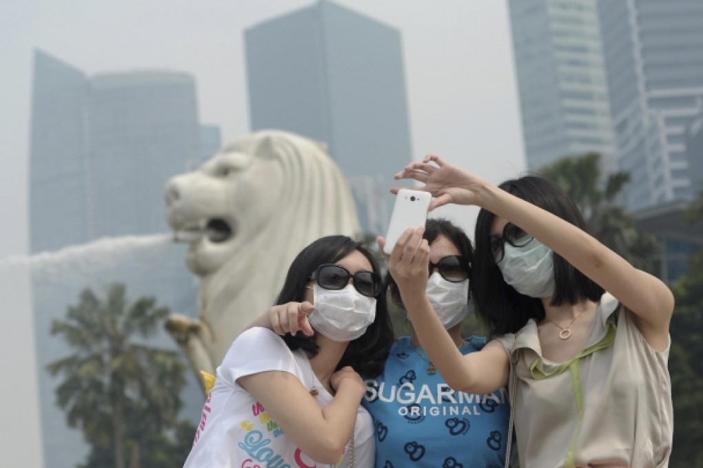 Tourists in masks and sunglasses at Singapore's Merlion. Photo: AP