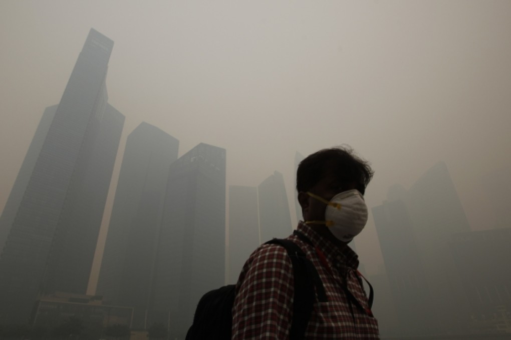 A man wearing a mask walks past the washed out skyline of Singapore's business district. Photo: Reuters