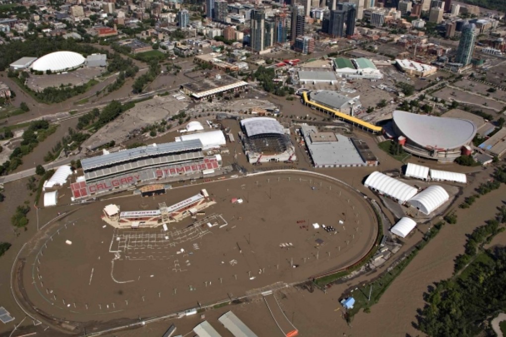 The Bow River overflows its banks into the grounds of the Calgary Stampede and Saddledome hockey arena (right). Photo: Reuters