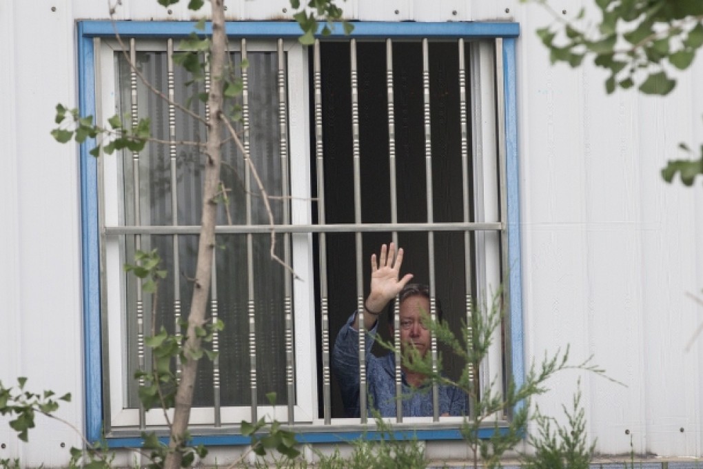 Chip Starnes waves from a window after he was held hostage by workers inside his plant at the Jinyurui Science and Technology Park in Qiao Zi near Beijing. Photo: AP