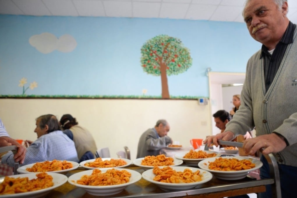 A volunteer with Caritas carries meals in a soup kitchen in Rome. Unemployment in Italy stood at 12 per cent in April, and the brain drain is worsening. Photo: AFP