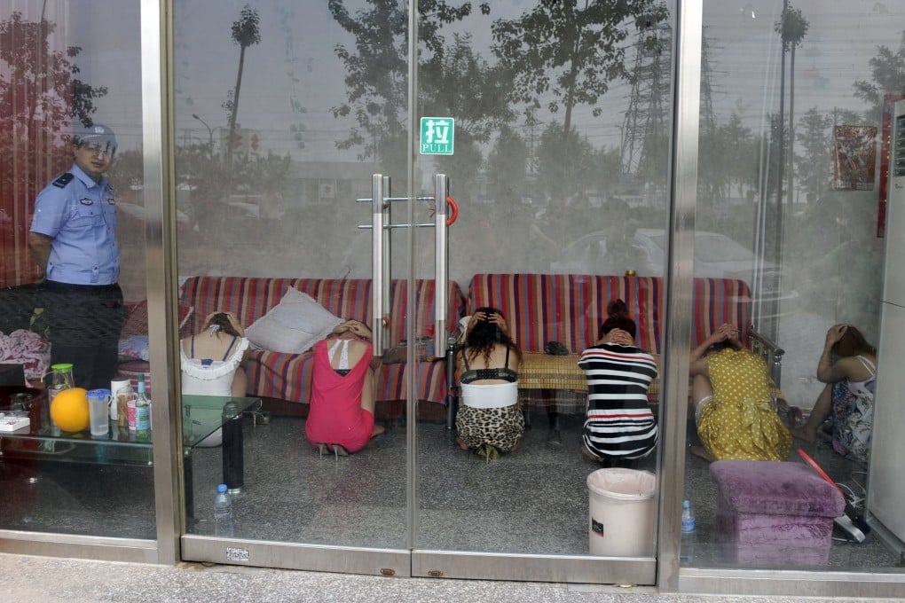 A policeman watches over a group of 'massage girls' suspected of prostitution during a raid on a parlour in Beijing. Photo: AP