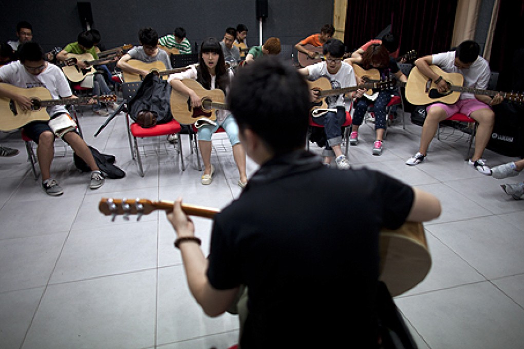 Students at Yuanjing Academy sing and play guitars at the College of Mobile Telecommunication in Chongqing. Photo: AP