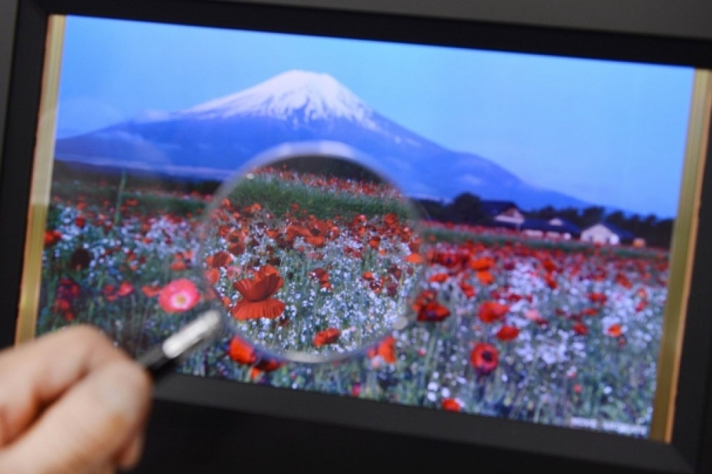 A magnifying glass is used to check an organic IGZO display, which is using new technology developed in part by Sharp. Photo: AFP