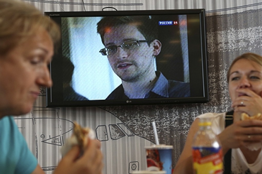 Transit passengers eat at a cafe at Sheremetyevo airport in Moscow as news about Edward Snowden broadcasts on television. Photo: AP