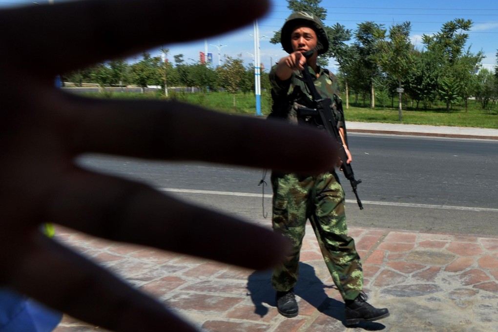 Chinese paramilitary police block photographers as they man a checkpoint on the road to the riot-hit Uigur town of Lukqun. Photo: AFP