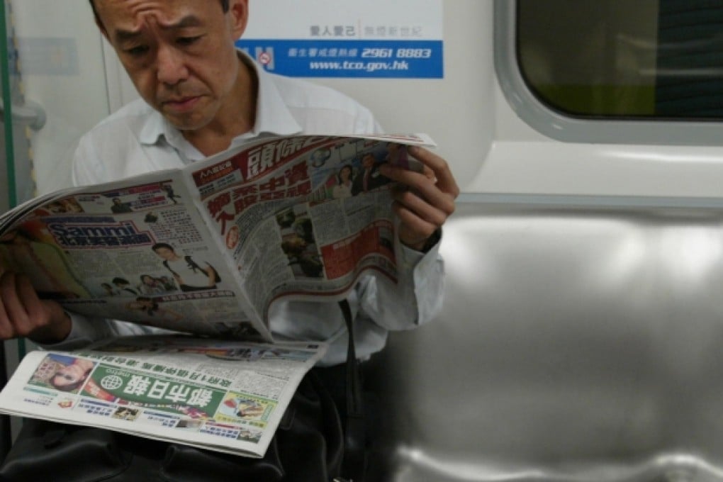An MTR rider gets his morning news from Headline Daily and Metro which has become the target of a possible takeover by Sing Tao News. Photo: SCMP