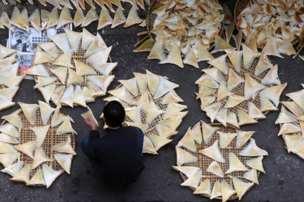 A worker in Western District dries shark fins outside a store. Photo: SCMP