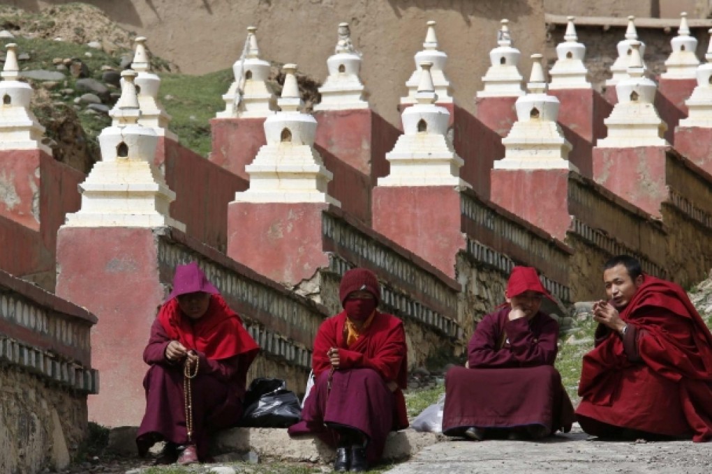 Monks sit at an entrance to the Dzamthang Jonang monastery, where a Tibetan woman set herself on fire. Photo: Reuters