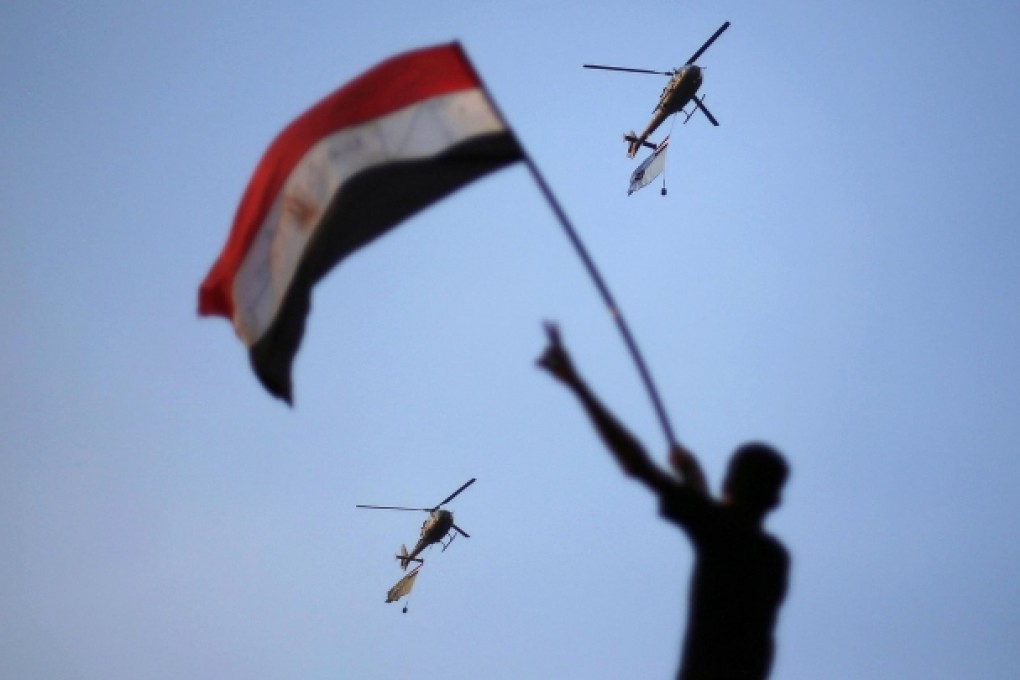 Military helicopters trailing national flags circle over Tahrir Square during the protest demanding Mohammed Mursi resign. Photo: Reuters