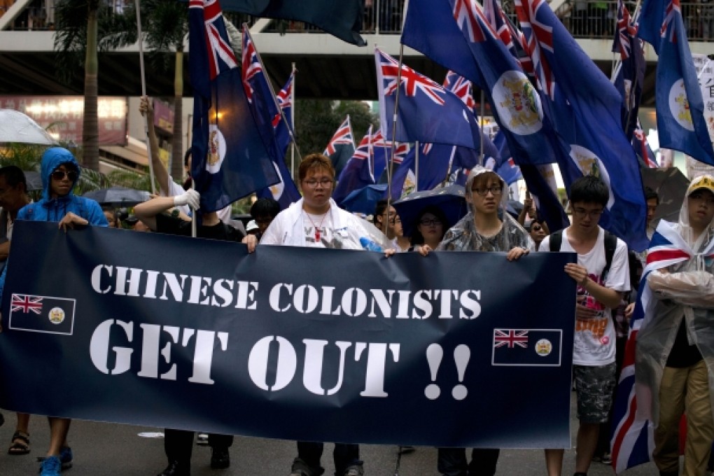 Protesters rallying for democracy on July 1, 2013 carry British-era Hong Kong flags and a banner that reads "Chinese Colonists Get Out!!" to mark the 16th anniversary of the establishment of the Hong Kong Special Administrative Region. Photo: AFP