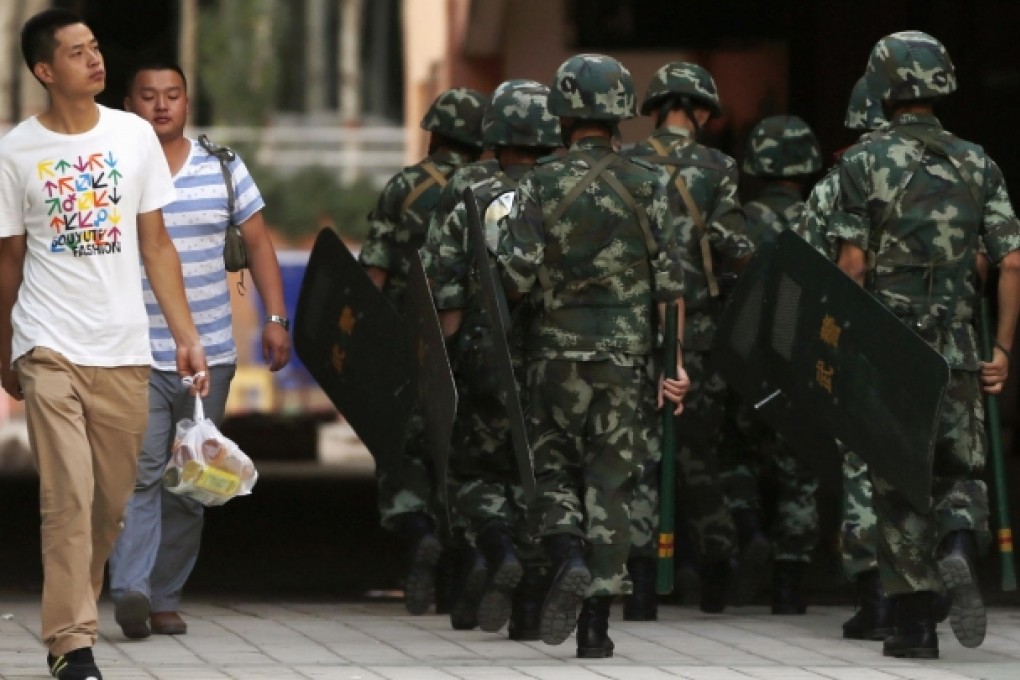 Residents walk past armed police in Kashgar. Photo: Reuters