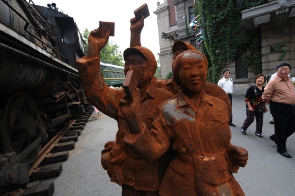 Chinese tourists walk past a rusted 1970's Cultural Revolution era statue showing Red Guards chanting political slogans in Shanghai. Photo: AFP