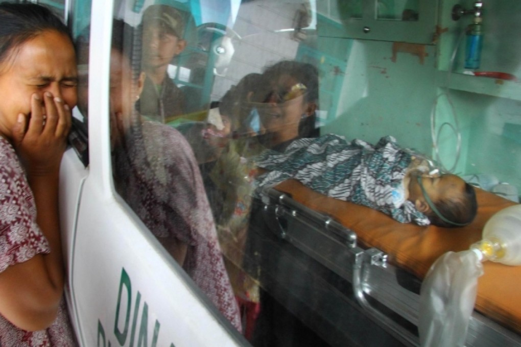A woman grieves over the body of her baby in an ambulance, one of the quake victims in Lampahan village. Photo: AFP