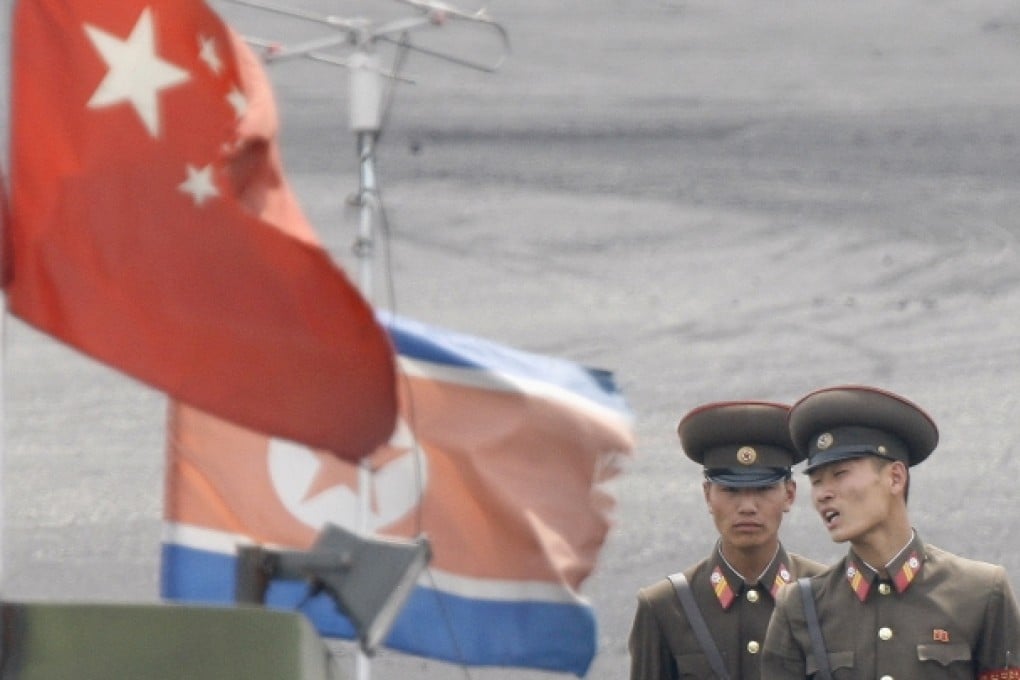 North Korean soldiers stand guard behind national flags of China and North Korea near the North Korean town of Sinuiju, opposite the Chinese border city of Dandong. Photo: Reuters