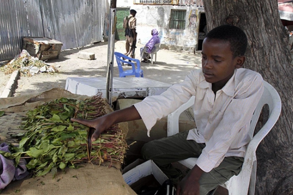 Isaq Abdi sits beside bundles of khat which he sells for his employer in Mogadishu, Somalia. Photo: AP
