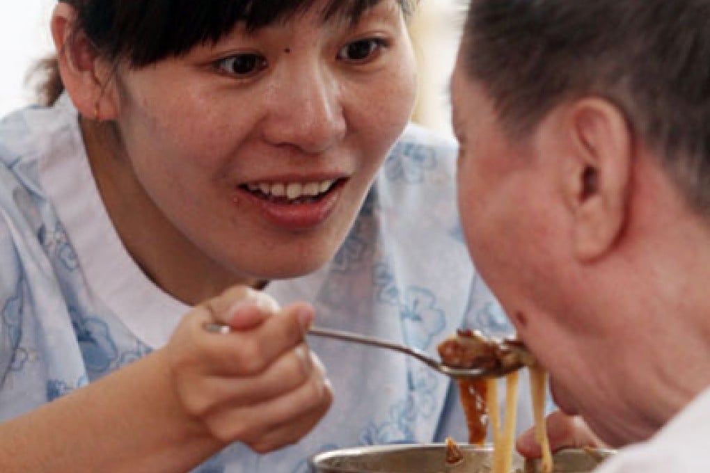 A staff member feeds a senior citizen at a rehabilitation care center in China. Photo: Xinhua