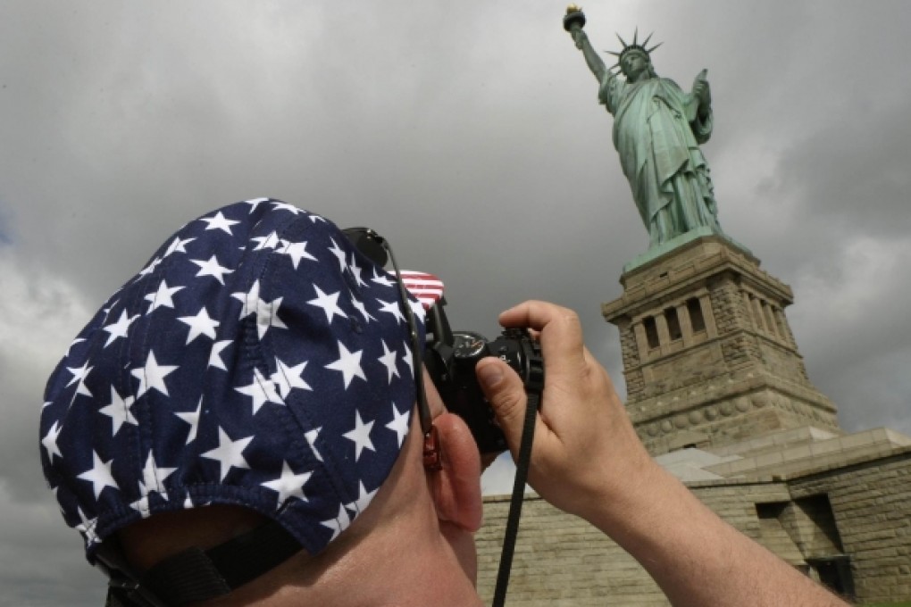 A visitor snaps a memento of the Statue of Liberty as it reopens to the public for the first time since Superstorm Sandy smashed into New York last October. Photo: AFP