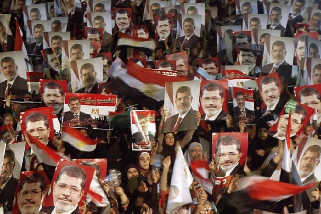 Members of the Muslim Brotherhood and supporters of the ousted Mohammed Mursi hold pictures of him in reaction to the military statement about his removal. Photo: Reuters