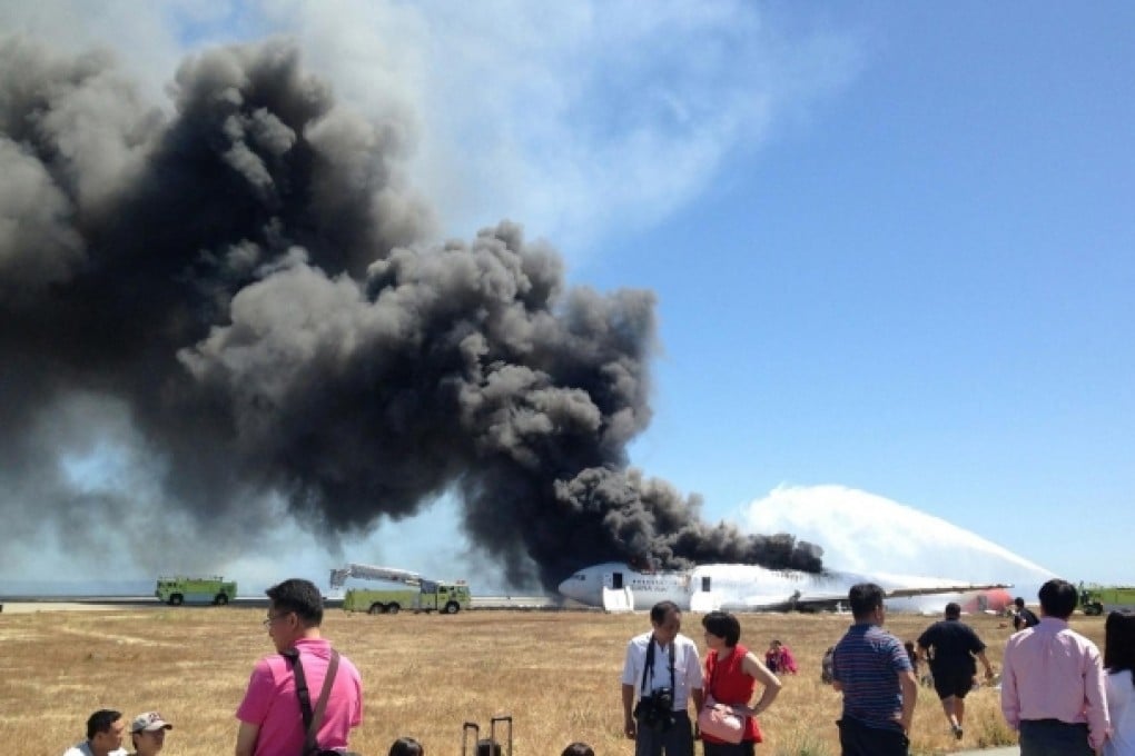 Evacuated passengers are seen on the tarmac as a firefighting truck sprays water on the ill-fated Asiana Airlines flight. Photo: Reuters