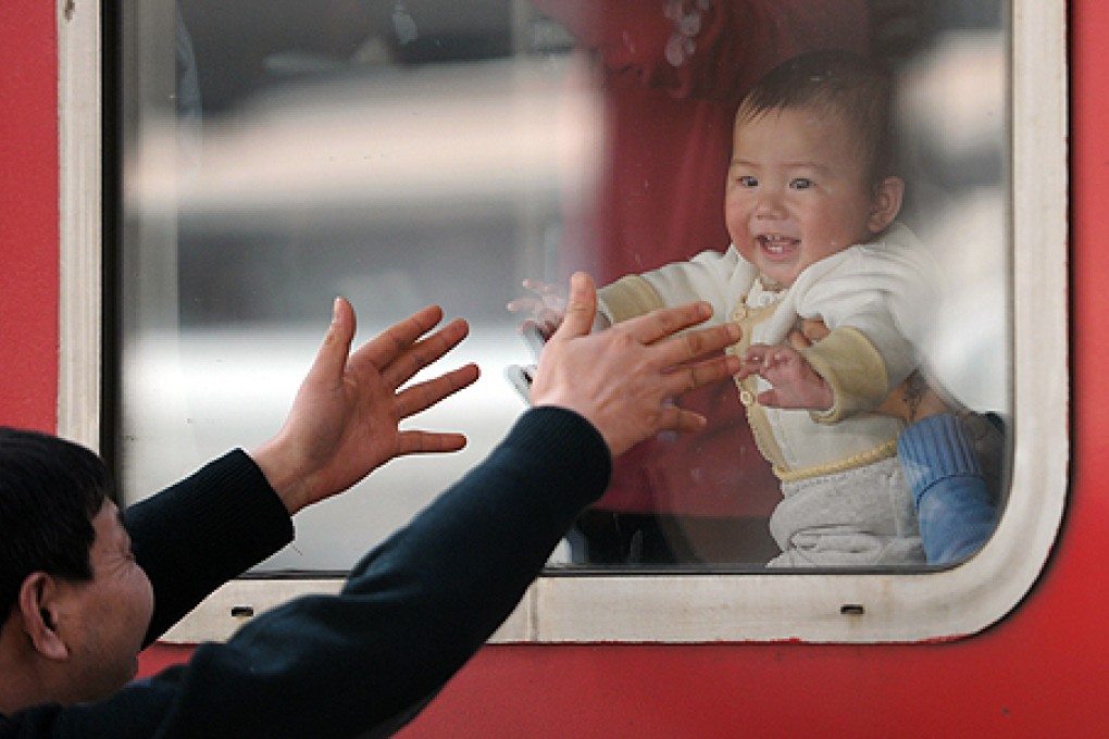 A man plays with his grandson who is aboard a train heading from Ningbo to Guangzhou in January. Photo: Xinhua