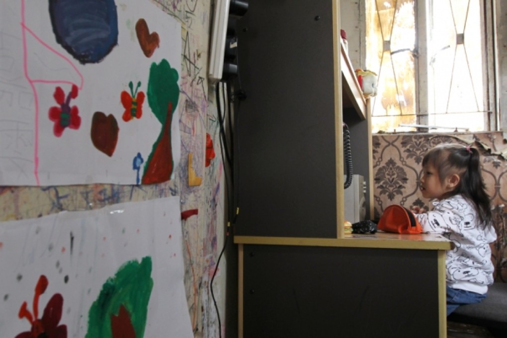 A girl who lives with her parents in a rooftop hut. Families living illegally on rooftops of industrial buildings say they cannot afford rents elsewhere. Photo: Felix Wong