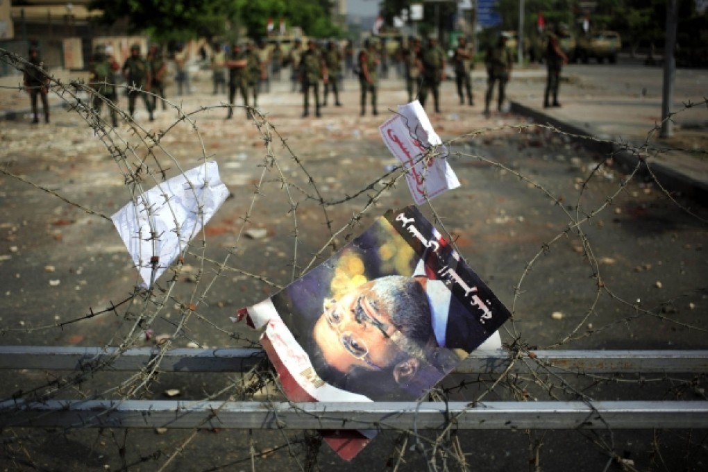 A poster of ousted president Mohammed Mursi hangs on barbed wire outside the Republican Guard building in pro-Mursi bastion Nasr City, Cairo. Photo: AP