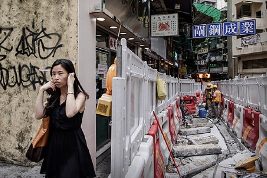 A woman blocks her ears as she walks past roadworks in Hong Kong. Photo: AFP