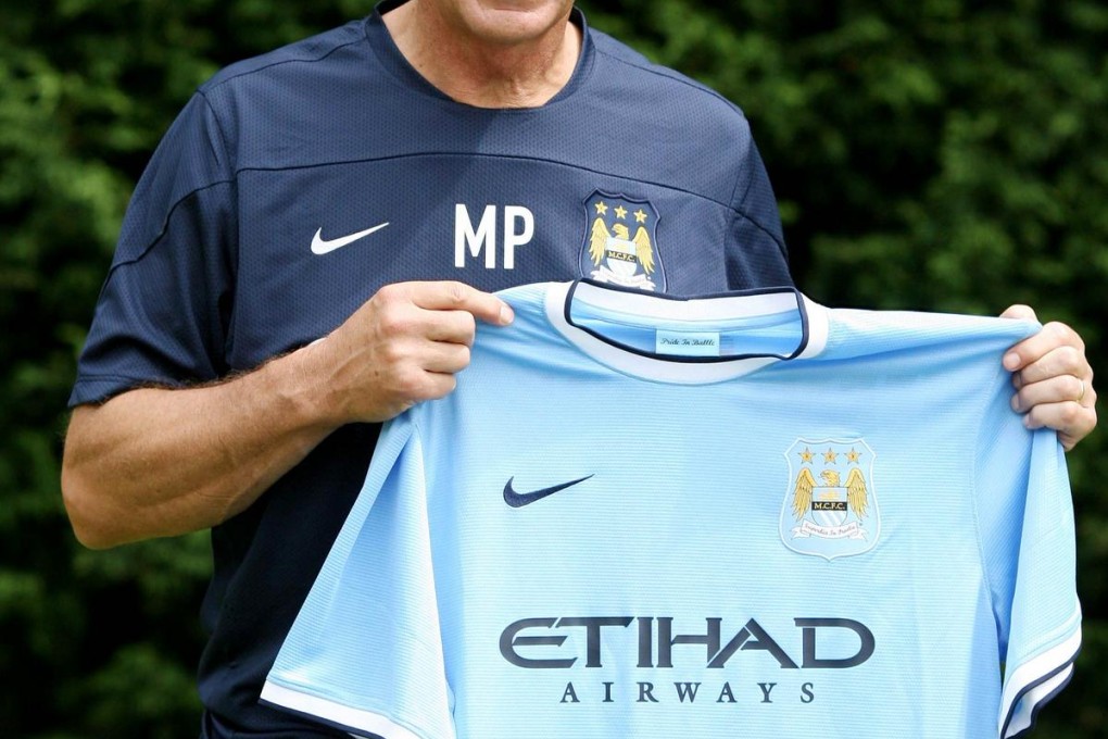 New Manchester City coach Manuel Pellegrini displays the jersey of his new allegiance at a press conference yesterday. Photo: AFP