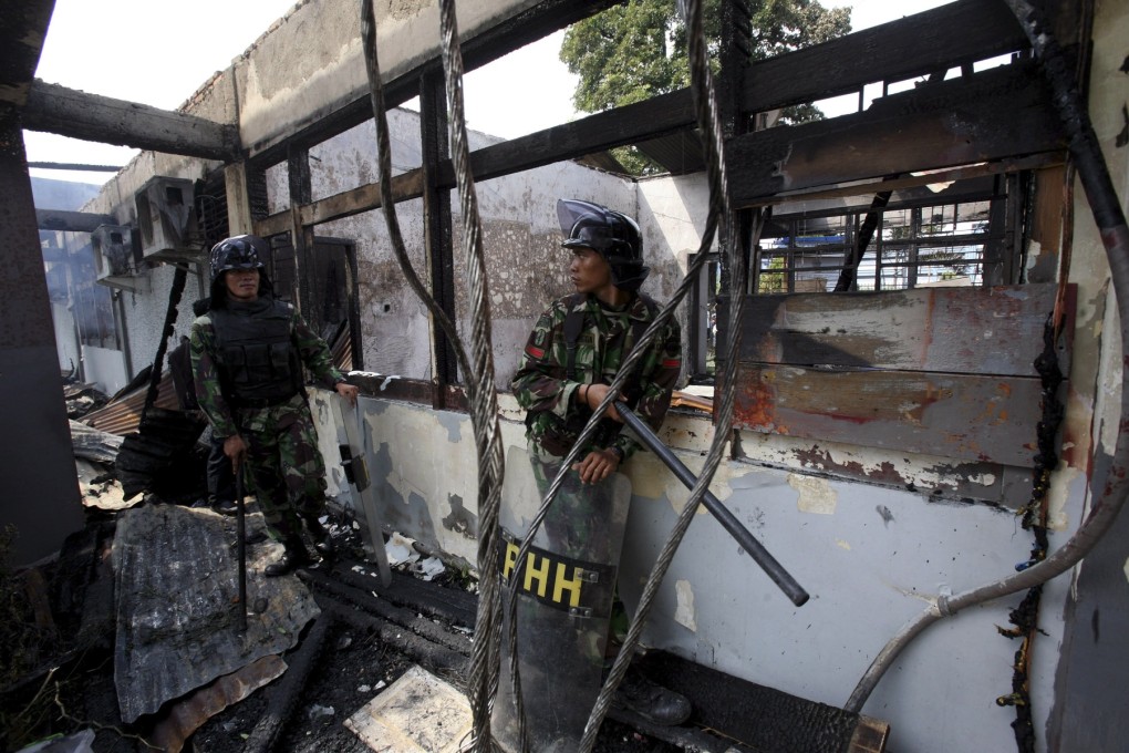 Indonesian soldiers stand guard in a burnt down room at Tanjung Gusta prison following a prison riot in Medan, North Sumatra. Photo: AP
