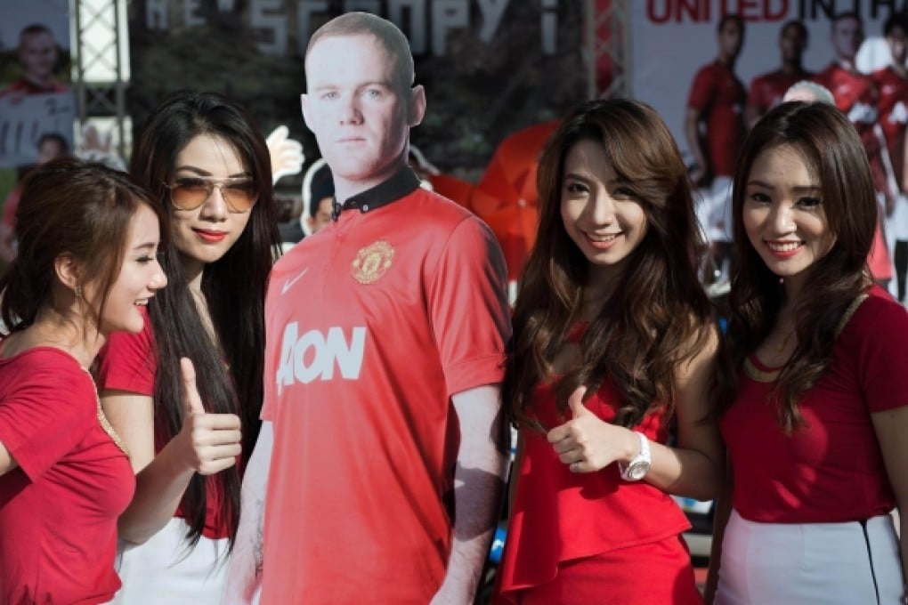 Thai models pose next to a life-sized cardboard cutout photograph of Manchester United's Wayne Rooney in Bangkok. Photo: AFP