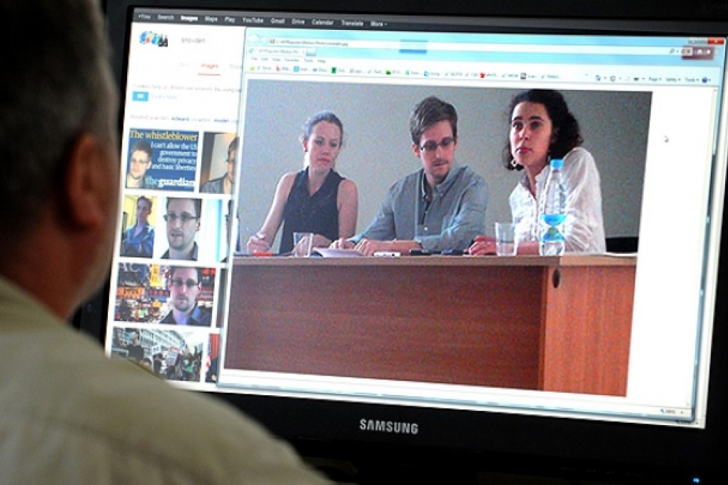 A screen in Moscow displays the first new photo in weeks of Edward Snowden, meeting with Russian activists and lawyers. Photo: AFP.