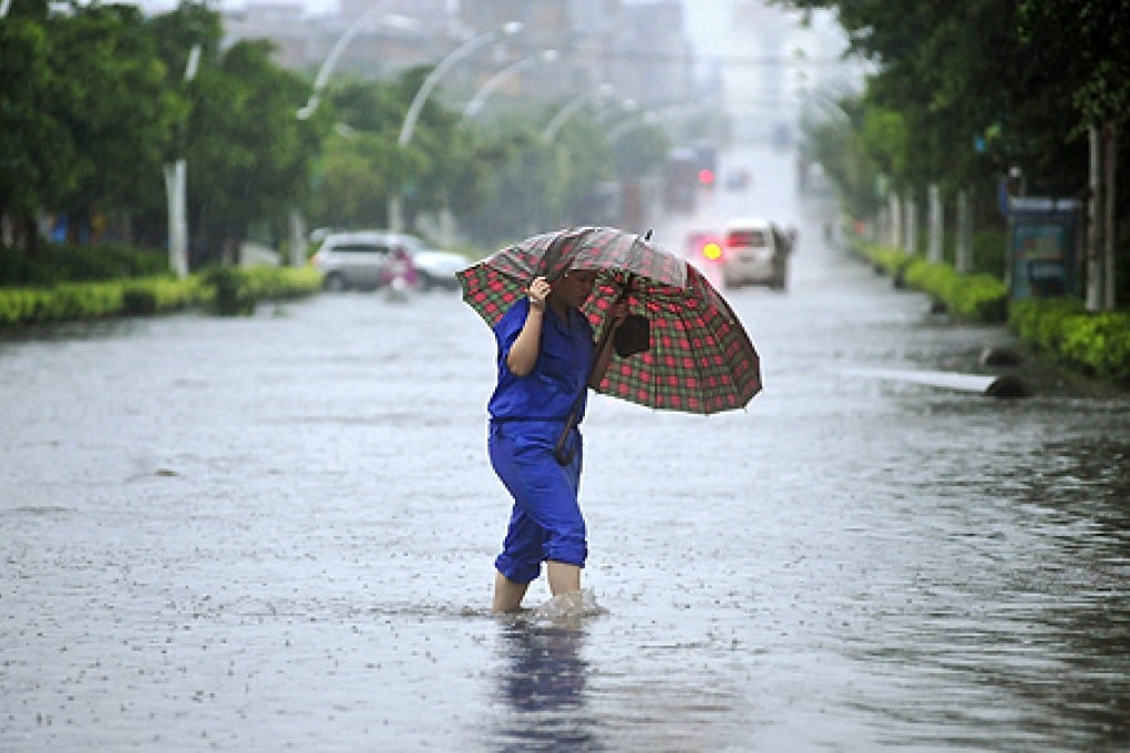 A worker holding an umbrella crosses a flooded street in Quanzhou, Fujian province, on Saturday. Photo: Reuters